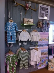 Baby romper suits and tiny dresses and jumpers at Lapstone- on brushed stainless rails.