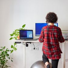 An ergonomic sit stand desk with a lady on a yoga ball An ergonomic sit stand desk with a lady on a yoga ball