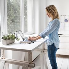 An ergonomic sit stand desk with a woman in a blue shirt An ergonomic sit stand desk with a woman in a blue shirt